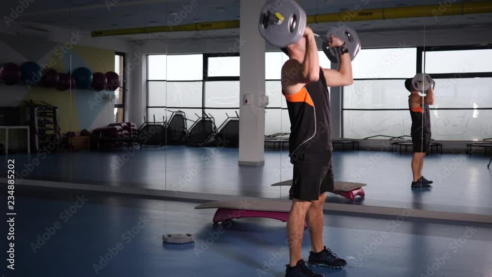 Young strong man in gym lifts weight having hard training workout Young strong man in gym lifts weight having hard training workout