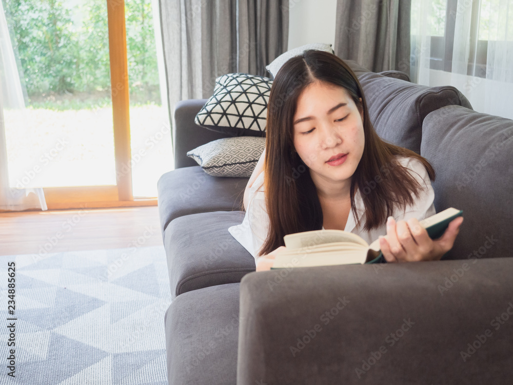 asian woman sitting and read book on sofa at home asian woman sitting and read book on sofa at home