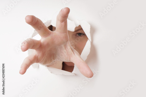 woman grabbing with hand through hole in paper wall  photo