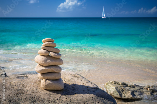 Stack of stones in balance at a beach with yacht on a background