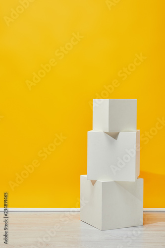 Minimalistic white plaster cubes arranged vertically near yellow wall