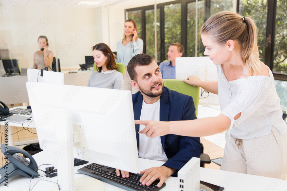 Fototapeta premium Successful businesswoman talking with guy colleague at computer monitor