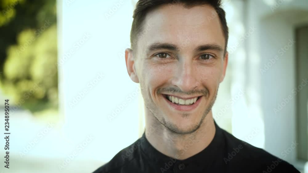 Portrait of laughing young man enjoying spending free time in city. Handsome caucasian brunette guy