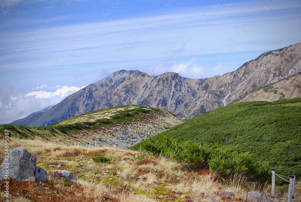 Highland in autumn time with mountain range and grass field above the cloud level in sunshine day 