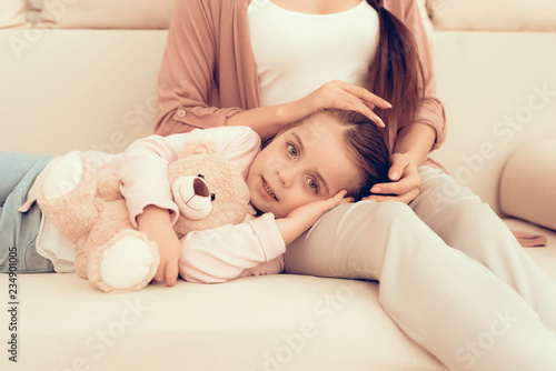Little Girl Lying on Knees on White Sofa at Home.
