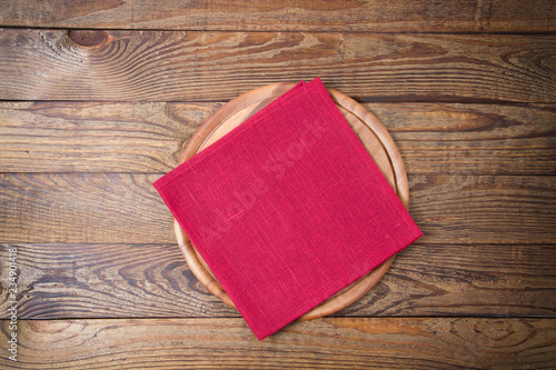 Brown old vintage wooden table with framed red tablecloth napkin and pizza cutting board.Thanksgiving day and Cristmas table concept. Top view and copy space. Selective focus