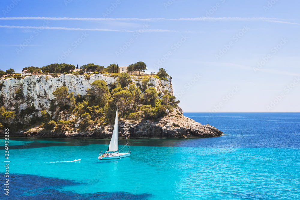 Obraz premium Piękna zatoka z żaglówką, Cala Galdana, wyspa Menorca, Hiszpania. Koncepcja żeglarstwa, podróży i aktywnego stylu życia