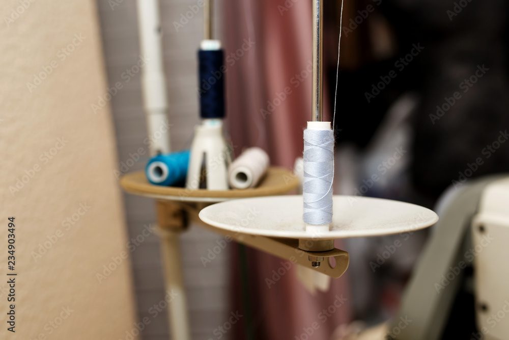 round plates of sewing machine with spools of threadsloaded into machine. Tailor industry concept round plates of sewing machine with spools of threadsloaded into machine. Tailor industry concept