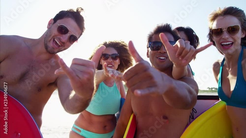 Portrait of multi ethnic friends in swimwear with bodyboards enjoying the beach 