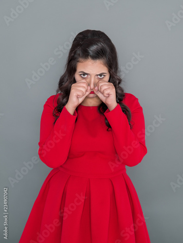 Sad plus size woman in red dress crying on gray