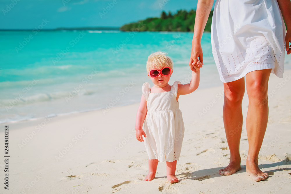 mother and cute little daughter walking on beach mother and cute little daughter walking on beach