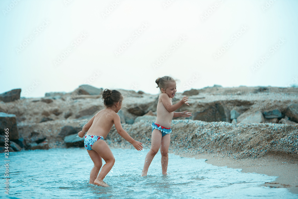 Two happy children playing on the sea beach at the sunny day time. The summer, childhood, holiday, leisure, lifestyle, travel, vacation concept Two happy children playing on the sea beach at the sunny day time. The summer, childhood, holiday, leisure, lifestyle, travel, vacation concept