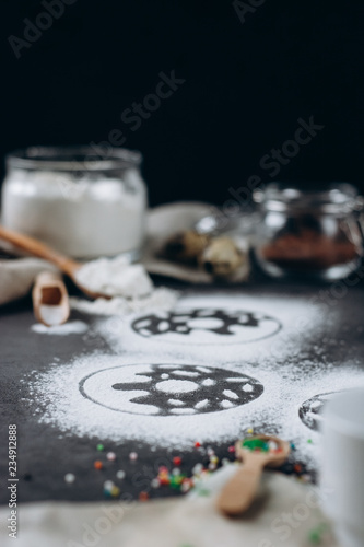 Ingredients for donuts baking. Spoon with flour  dishes  eggs  sugar  on a grey background.Bakery background frame. Top view  copy space.