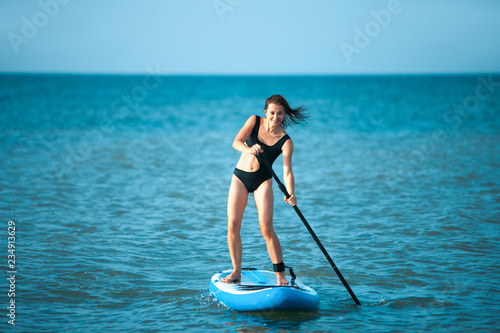 Photography Happy beautiful young girl with paddle board on a tropical beach
