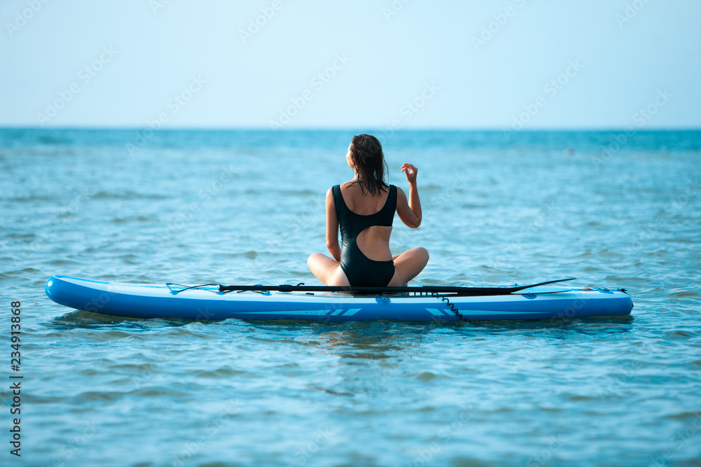 Happy beautiful young girl with paddle board on a tropical beach. Blue sea in the background. Summer, vacation, sup paddleboarding or surfing, travel, lifestyle concept. Happy beautiful young girl with paddle board on a tropical beach. Blue sea in the background. Summer, vacation, sup paddleboarding or surfing, travel, lifestyle concept.