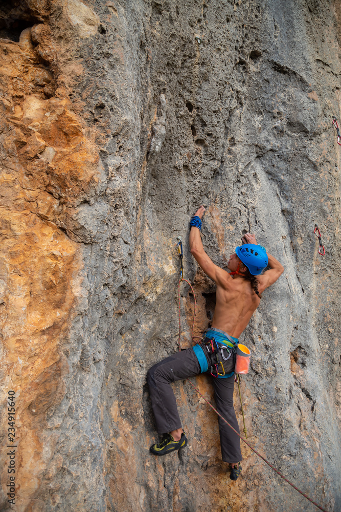 Shirtless climber man climbing mountain wall on amazing sunny day Shirtless climber man climbing mountain wall on amazing sunny day