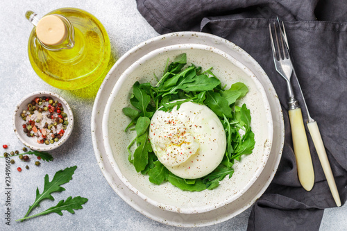 Delicious Creamy Italian Burrata Cheese Served with Olive Oil, fresh arugula and spices in a white plate
