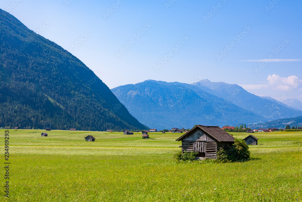 huts for storing materials and hay on a green meadow in the austrian alps