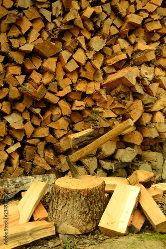 siekiera wbita w pień na tle porąbanego drewna