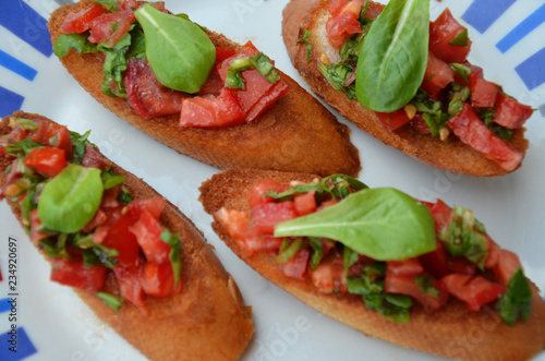 Traditional italian bruschetta with cherry tomatoes, cream cheese, basil leaves, capers and balsamic vinegar on plate. Close up view