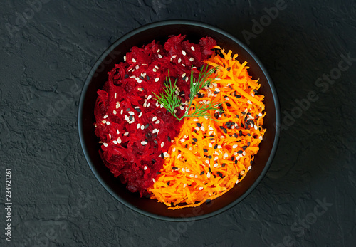 Obraz na płótnie Raw vegan salad with fresh beetroot and carrot flavored with olive oil and sesame seeds on dark concrete background