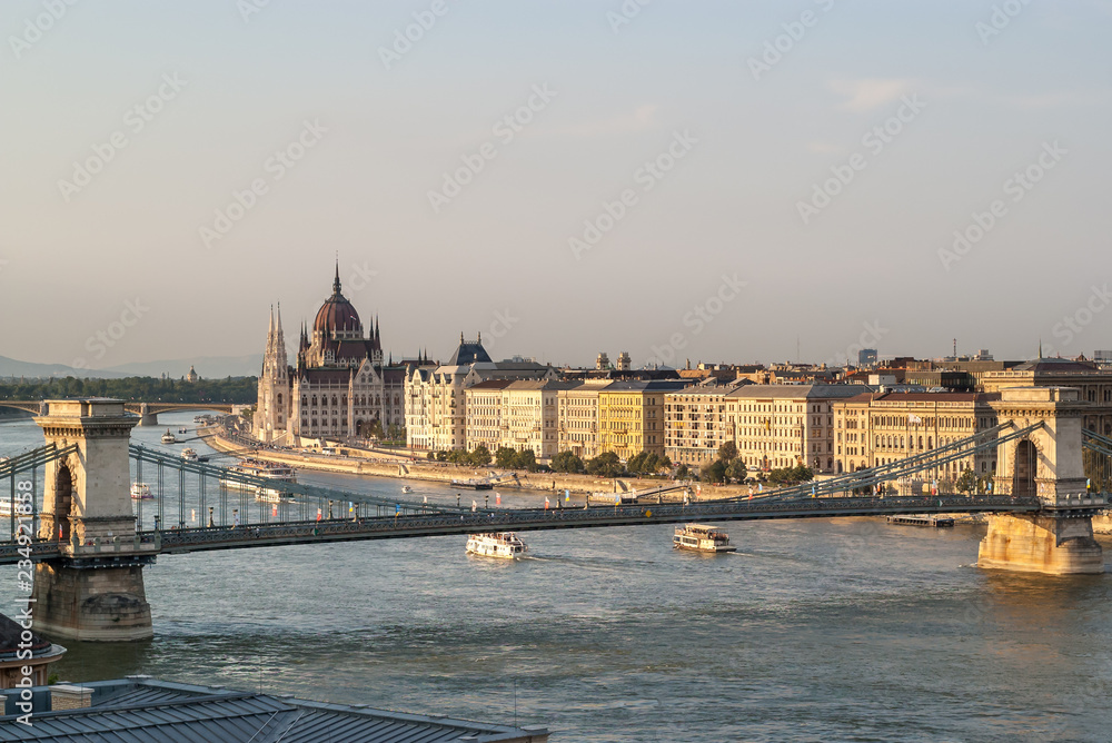 Obraz premium Panoramic view from the Castle hill in Budapest during sunset of the Hungarian Parliament building, the Chain Bridge of the Danube with cruise ships and the buildings on the river bank. 