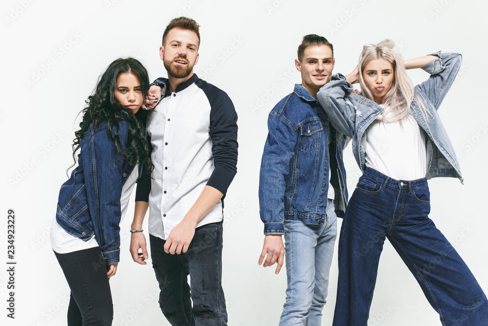 Group of smiling friends in fashionable jeans. The young men and woman posing at studio. The fashion, people, happy, lifestyle, clothes concept Group of smiling friends in fashionable jeans. The young men and woman posing at studio. The fashion, people, happy, lifestyle, clothes concept