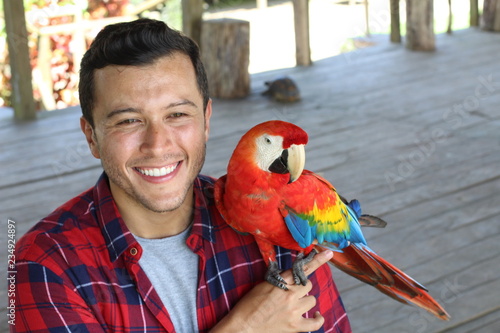 Handsome ethnic man holding and colourful macaw