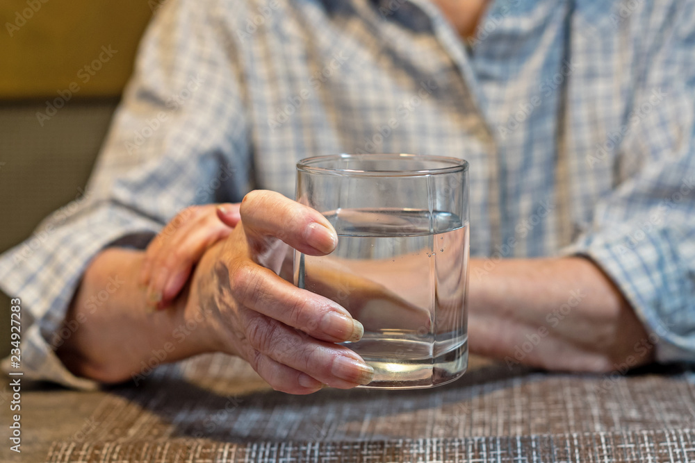 old women's hands holding a glass of water