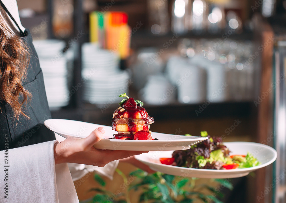Waiter serving in motion on duty in restaurant. The waiter carries dishes Waiter serving in motion on duty in restaurant. The waiter carries dishes