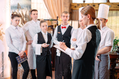 restaurant manager and his staff in kitchen. interacting to head chef in commercial kitchen.