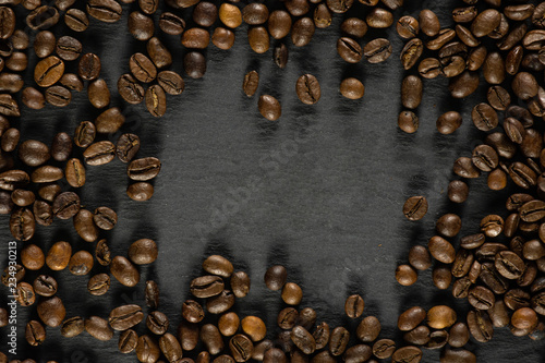 Lot of whole dark brown coffee beans sweet arabica variety frame flatlay on grey stone