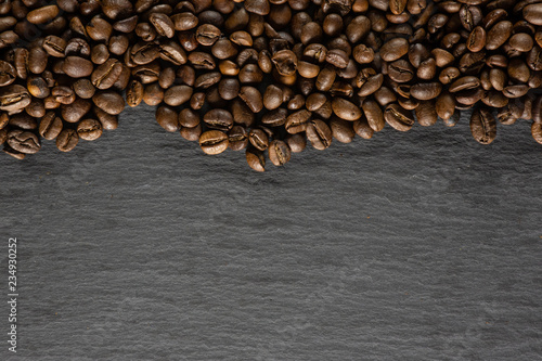 Lot of whole dark brown coffee beans sweet arabica variety above flatlay on grey stone © PIXbank