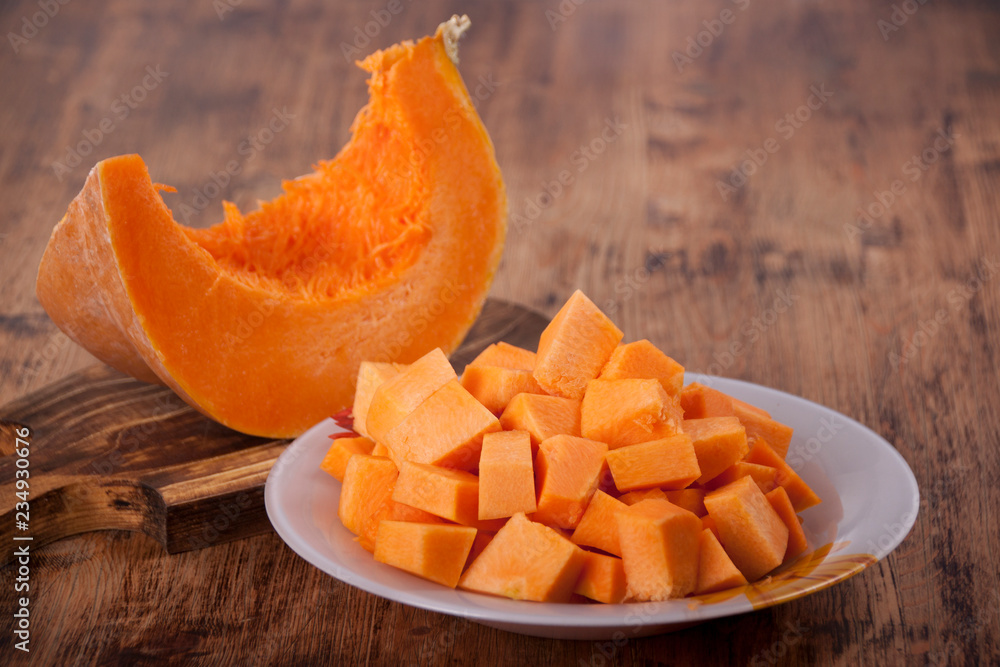 Slices of pumpkin in a plate on an old wooden table Slices of pumpkin in a plate on an old wooden table