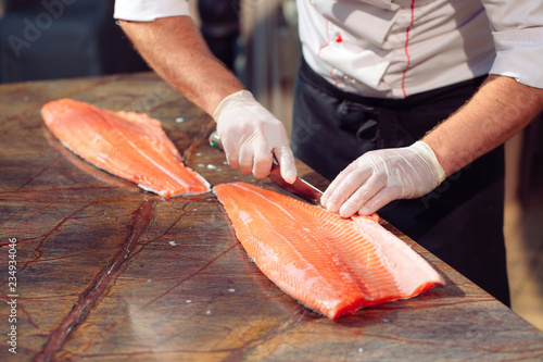 The chef cuts the salmon on the table.