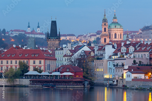 Prague - St. Nicholas church on Mala Strana, gothic tower of Charles bridge and Strahov monastery in the background in morning.
