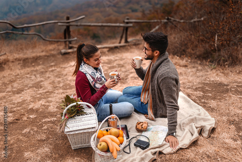 Happy couple hugging and making a toast outdoors while looking at camera. Autumn season. Forest and mountains in background.