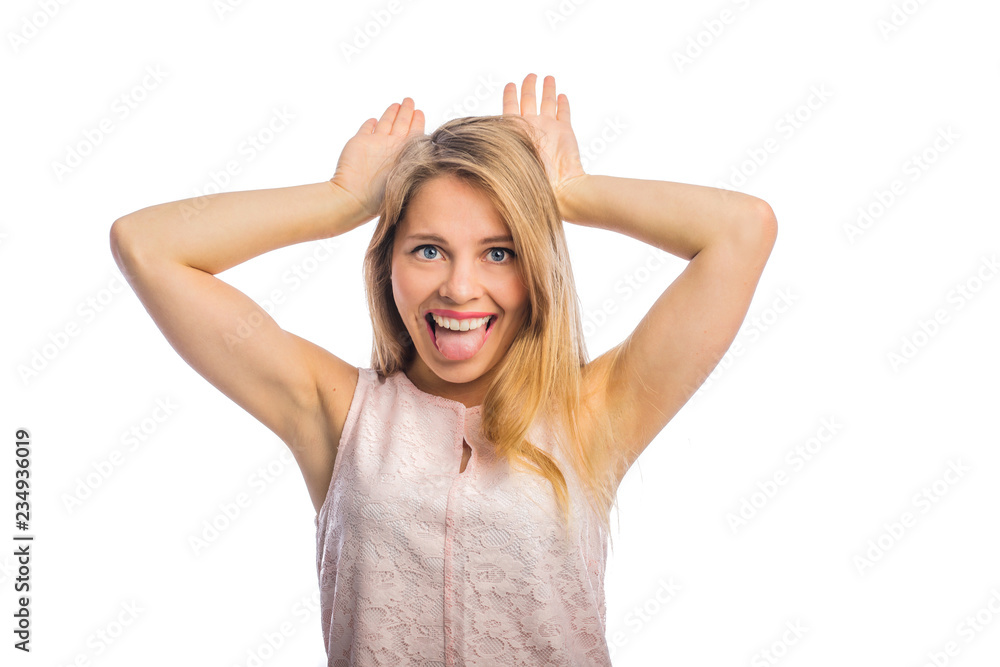 A close-up photo of a pretty woman who is fooling around showing tongue and horns with her hands on her head, a cheerful mood