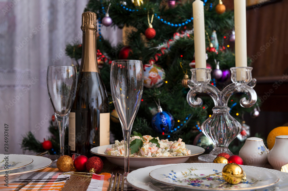 Naklejka premium festive table set, plates, fork, Olivier salad, red, Golden Christmas balls, napkins, food, new year, Christmas, glasses, Christmas tree, bottle of sparkling wine,