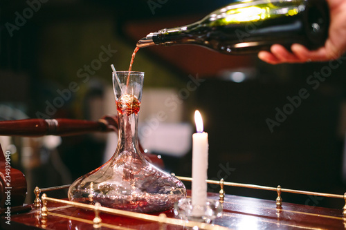 A sommelier pouring red wine into decanter