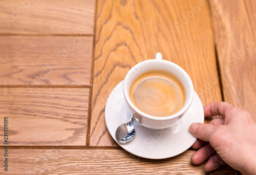 man's hand holding a Cup of coffee on a saucer