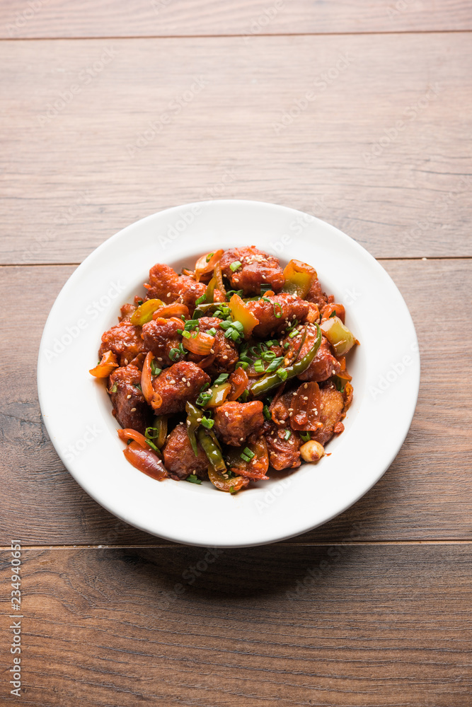 Indian Chilli Chicken dry, served in a plate over moody background. Selective focus Indian Chilli Chicken dry, served in a plate over moody background. Selective focus