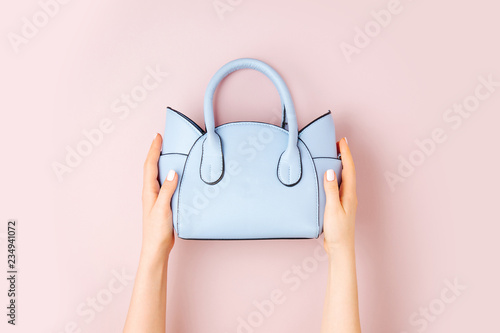 Female hands holds handbag on pink  background . Flat lay, top view. Spring fashion concept in pastel colored photo