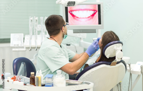 young woman sitting in the dentist s chair with opened mouth at dentist s office while having examination.