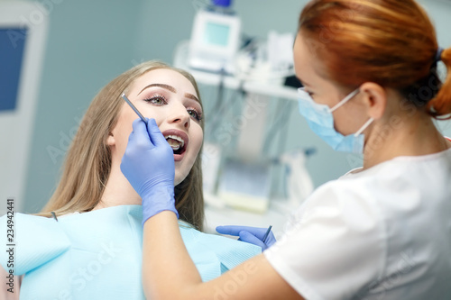 female dentist checking patient girl teeth