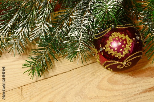snow-covered Christmas tree branch with Christmas balls on wood. Xmas background