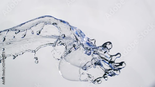 Running water with blue reflectios falling down in front of white background in slowmotion photo