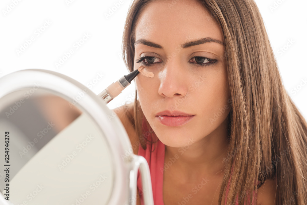 Beautiful young woman applying make up with a brush on white background Beautiful young woman applying make up with a brush on white background