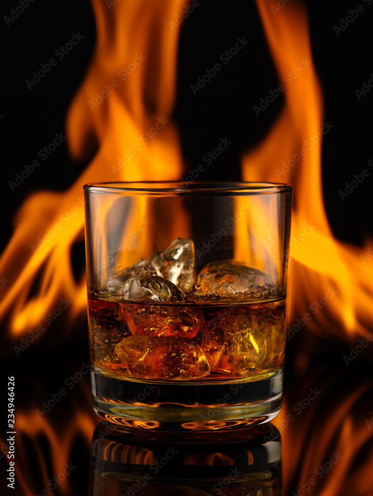 Glass of whiskey with ice on a background of fire. Glass of whiskey with ice on a background of fire.
