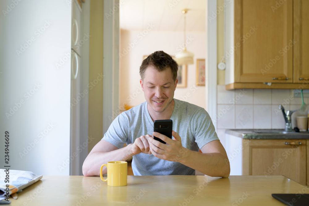 Young Happy Man Using Phone By The Window Young Happy Man Using Phone By The Window